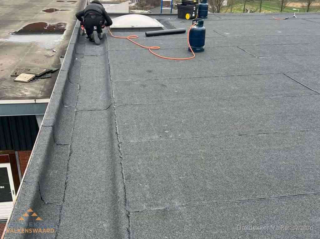 Dakdekker repareert bitumen dakbedekking op groot plat dak in Valkenswaard