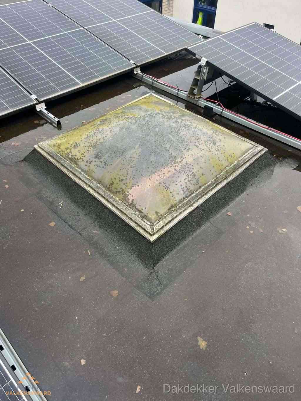 Vervuilde lichtkoepel op plat dak met zonnepanelen in Valkenswaard