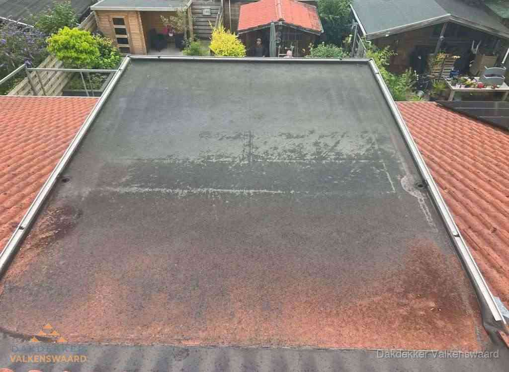Verouderd plat dak met slijtage tussen schuine daken in Valkenswaard